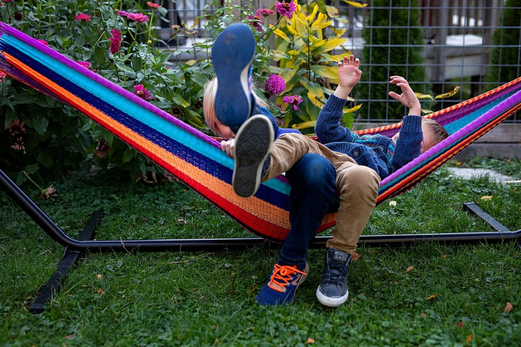 Two kids, with legs in the air, while playing in hammock during photographing kid personalities. 