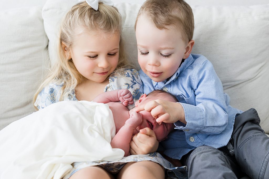 Big Sister and Big Brother touching new baby
