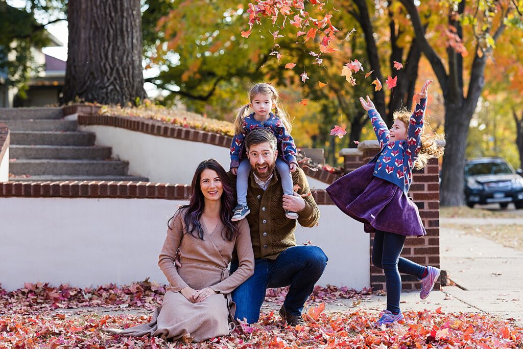 Family throwing leaves in the air in the fall in St. Paul, MN
