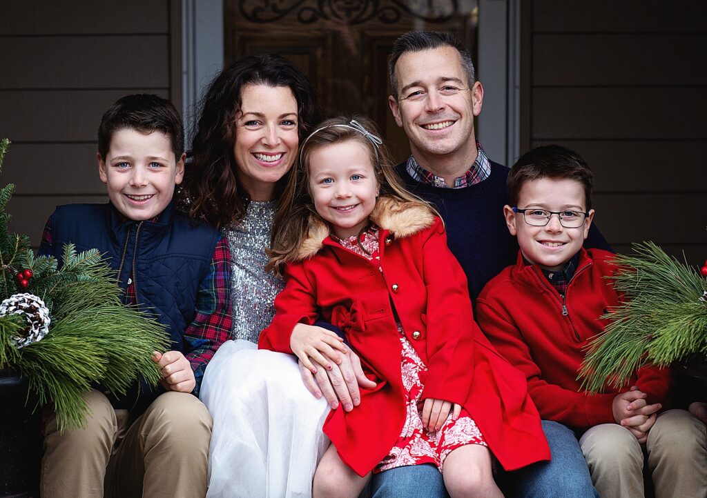 Winter family photos in reds and plaids on their front step in Mendota Heights, MN during 5 fun ideas for family photos in winter.