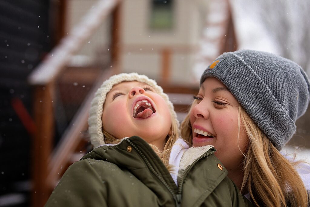 Mother and daughter catching snowflakes on their tongues in Eden Prairie, MN for family photos during 5 fun ideas for family photos in winter.
