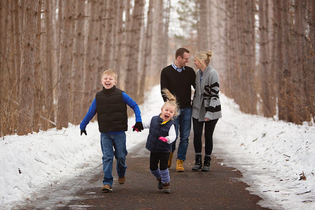 Family in the winter running through the trees in Chaska, MN