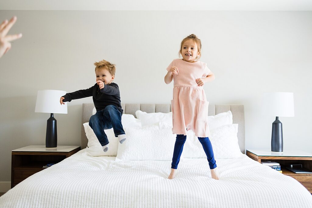 Kids jumping on bed at family session with Edina Photographer