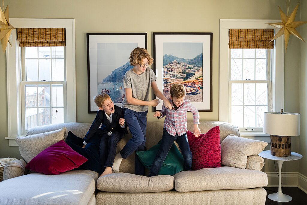 Three brothers jumping on the couch for family photos in 7 Huge Reasons to Book Your In-Home Family Photo Session.