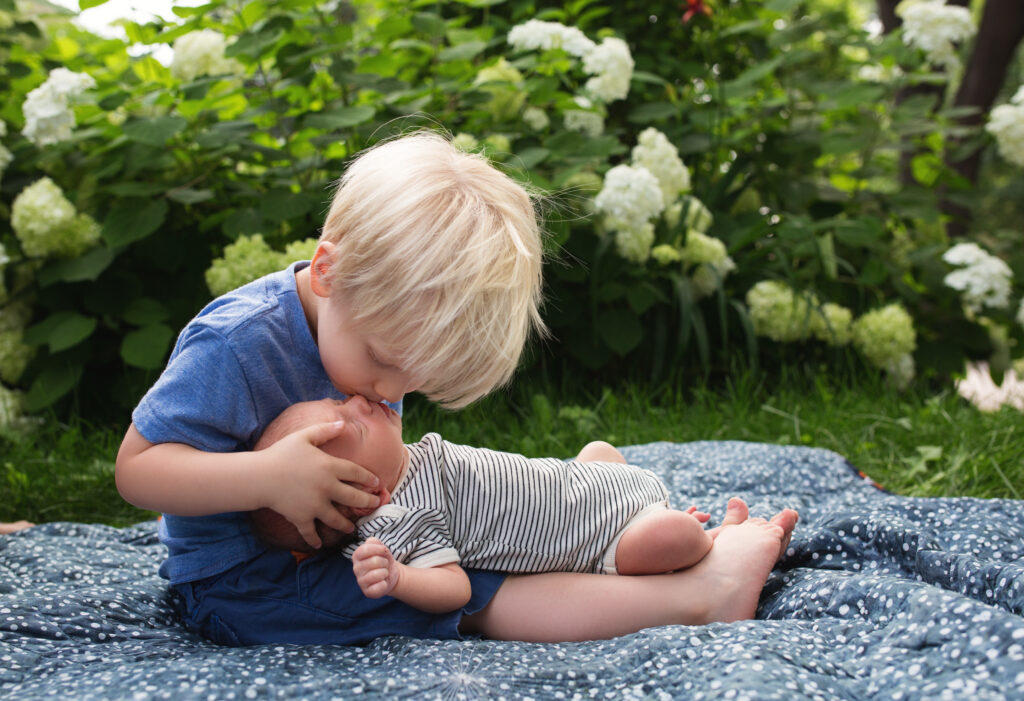 a photo of a little boy kissing his baby brother- how to keep toddlers engaged during family photos