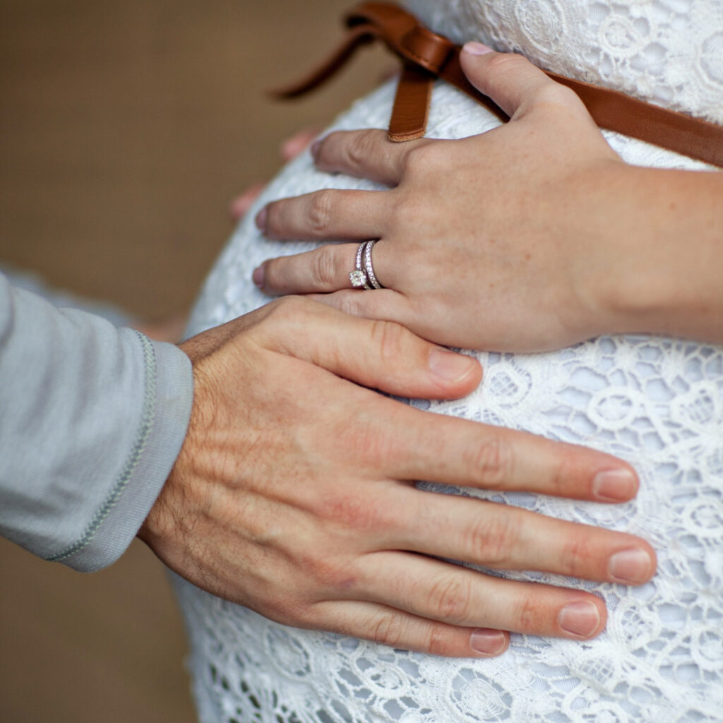 Hands resting gently on a baby bump, symbolizing love, anticipation, and the journey to parenthood.