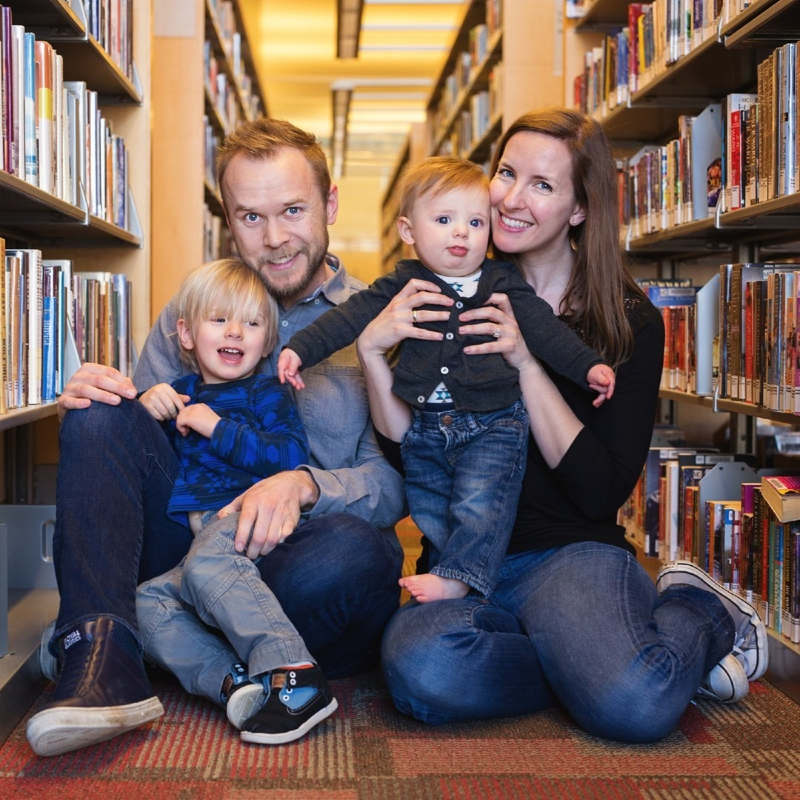 Family shares a playful moment between library shelves, showing creative indoor photo locations in Minneapolis.