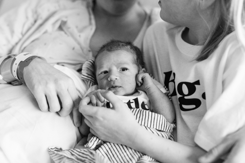 Newborn held by sibling and mom during fresh 48 session, a tender moment tied to what to pack in your hospital bag.