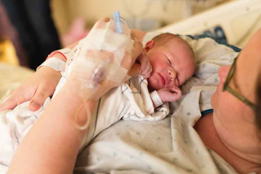 A new mom gazes at her swaddled newborn during a Fresh 48 session in her Minnesota hospital room.