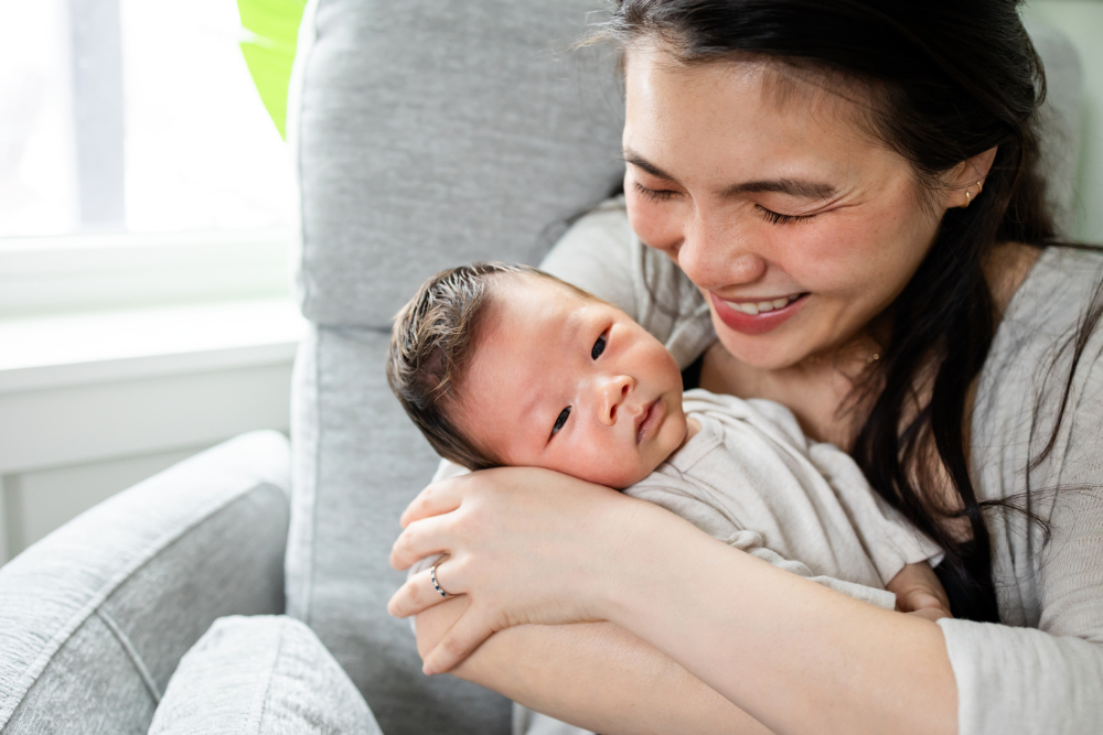 A Minnesota mom smiling while holding her newborn, the kind of postpartum connection therapy for women can help protect 
