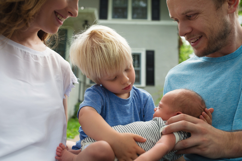 A family gathers around their newborn as an older sibling reaches in to connect, capturing the love and transition that come after Birth Plans become real life.