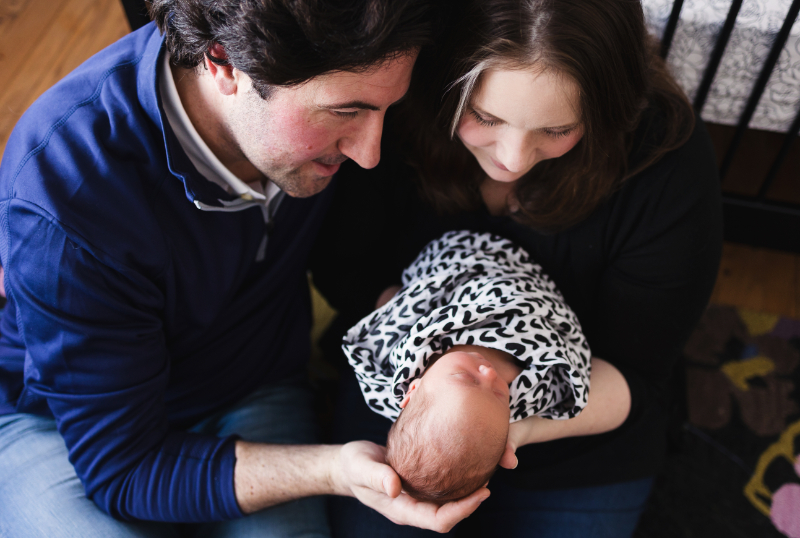 New parents look down at their swaddled baby at home, capturing the tender early days of parenthood and the life waiting on the other side of Birth Plans.