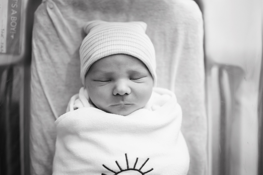 Black-and-white Fresh 48 photo of a sleeping newborn swaddled in a hospital bassinet, capturing the first sweet moments after birth in the Twin Cities.